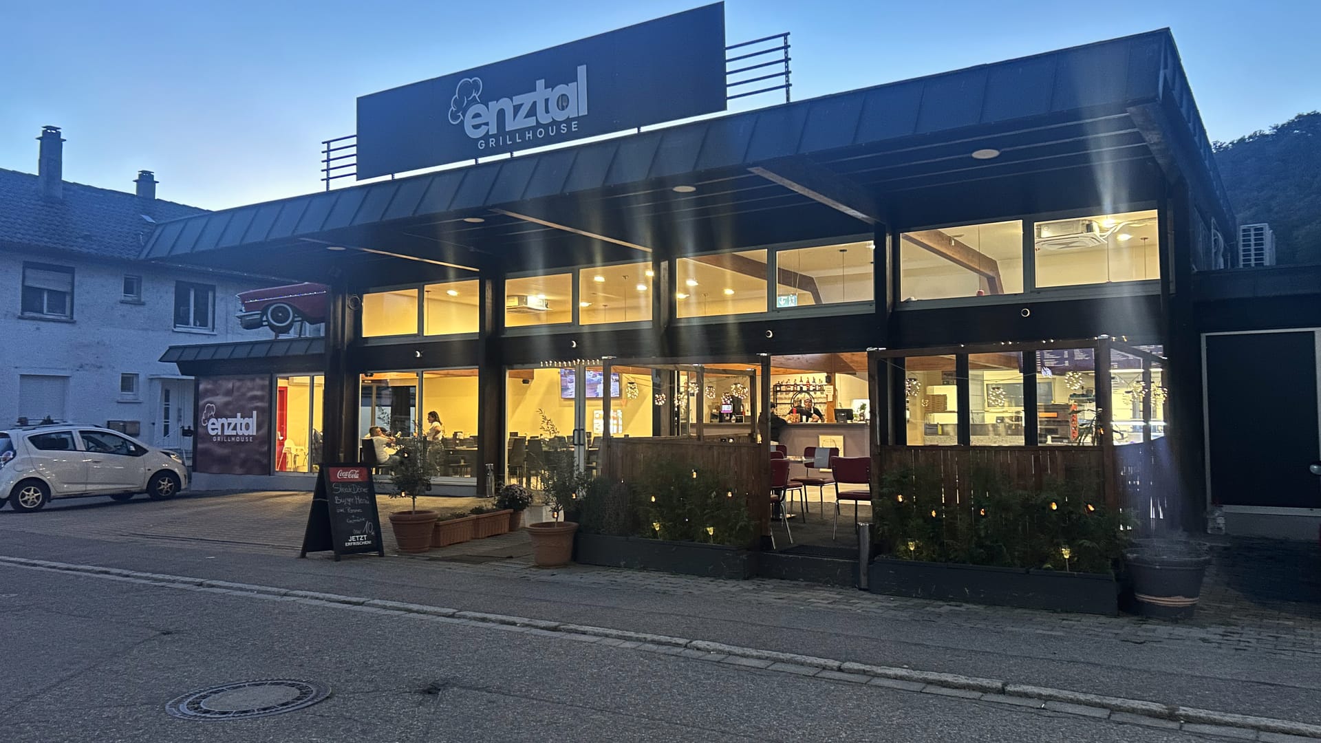 Enztal Grillhouse am Abend: beleuchtete Glasfront mit Terrasse an der Enztalstraße 1